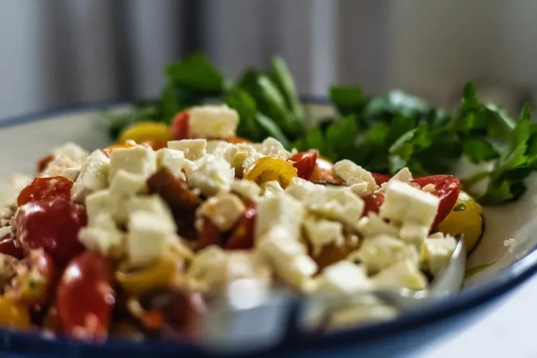 Colorful Mediterranean salad with feta cheese, cherry tomatoes, cucumber, red onion, and kalamata olives in a white bowl