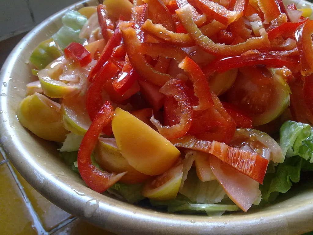 Fresh Mediterranean salad in a white bowl with feta cheese, cherry tomatoes, cucumbers, red onions, and olives