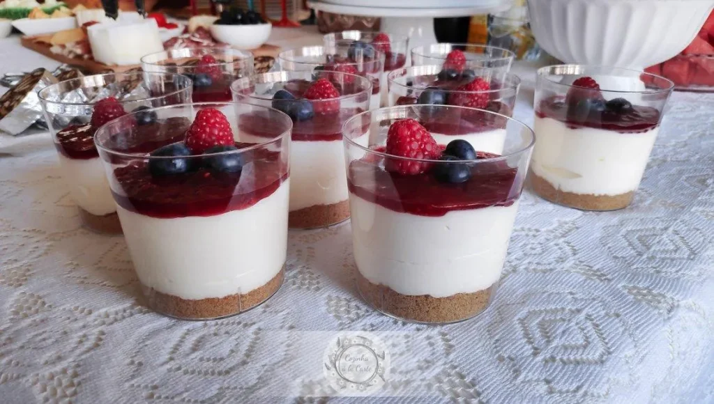 No-bake cheesecake cups topped with fresh raspberries and blueberries in small dessert glasses