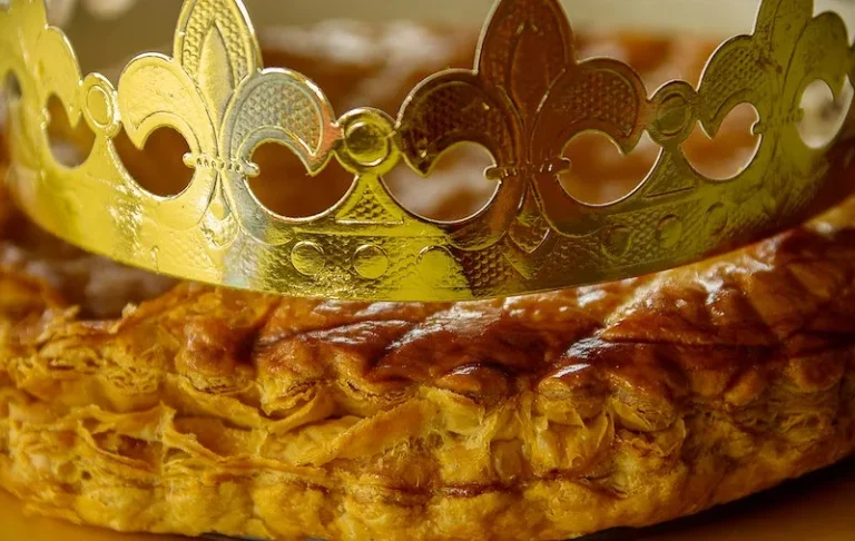 Traditional Galette des Rois with golden puff pastry, paper crown, and almond frangipane filling