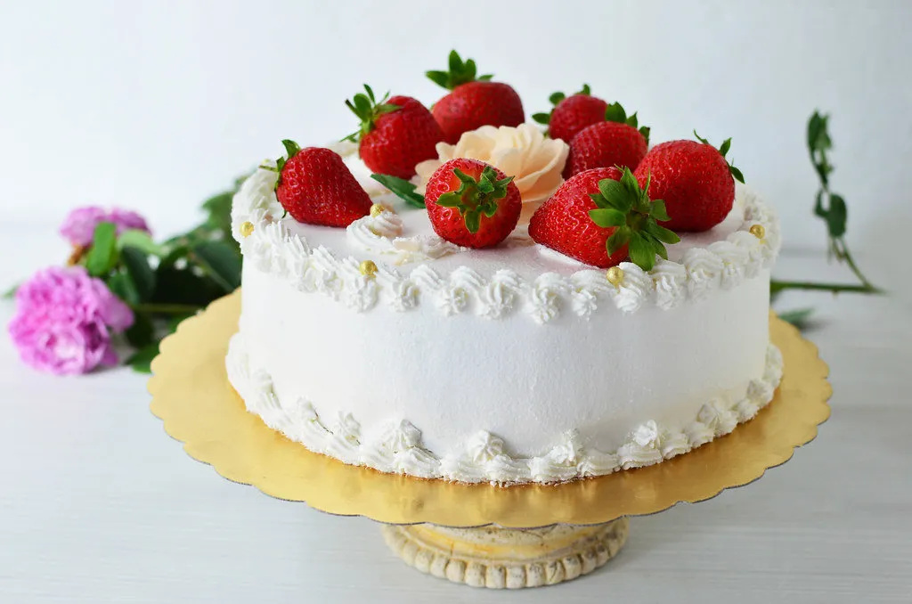 Classic Italian Cream Cake with cream cheese frosting, topped with toasted pecans and coconut flakes on a cake stand