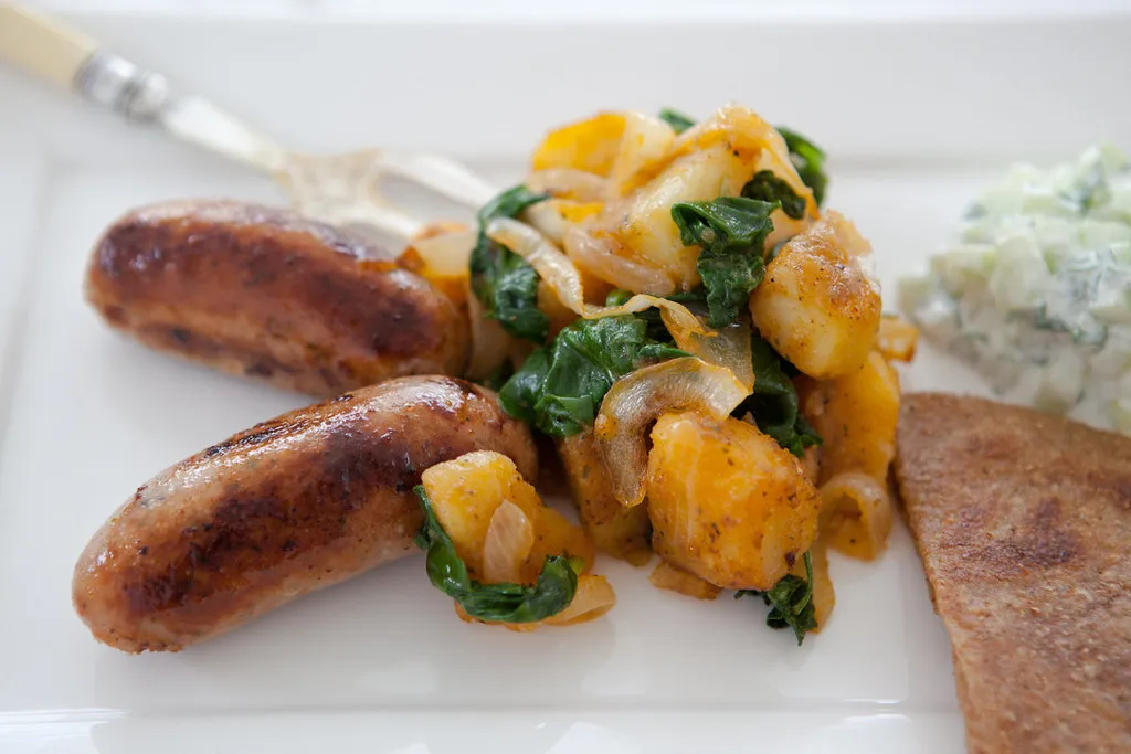 Hearty breakfast skillet with crispy potatoes, spicy sausage, sautéed peppers, and sunny-side-up eggs