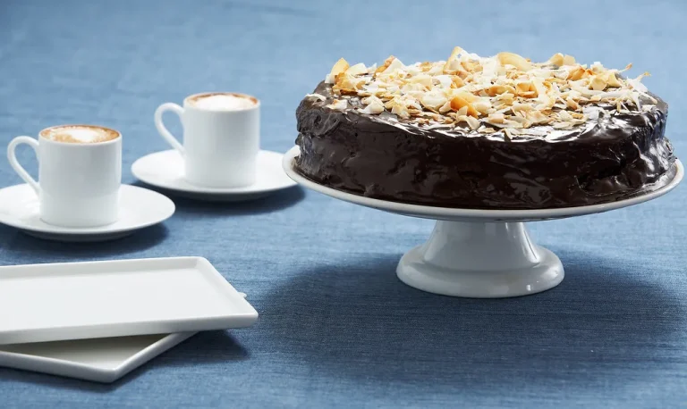 Homemade papaya cake topped with powdered sugar and served on a white plate with fresh papaya slices