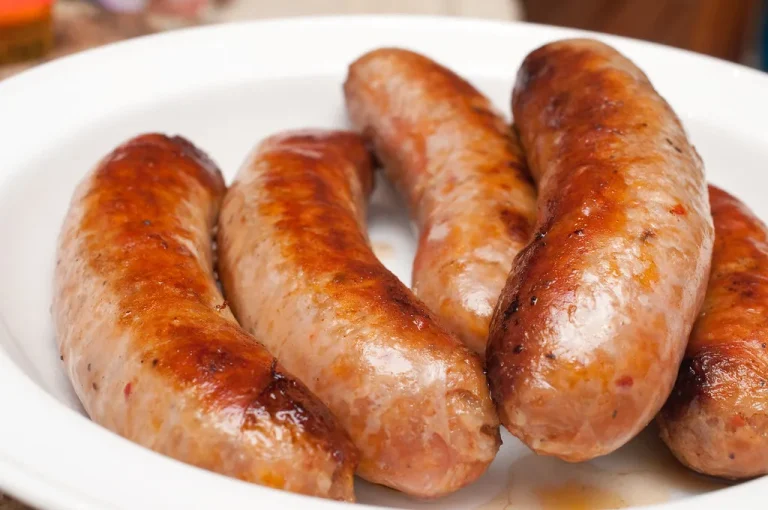 Grilled hot sausages served on a rustic board with roasted vegetables, fresh herbs, and spicy mustard on the side