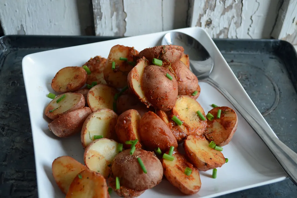 Golden baked baby potatoes with crispy skins, seasoned with herbs and garlic, served in a rustic dish.