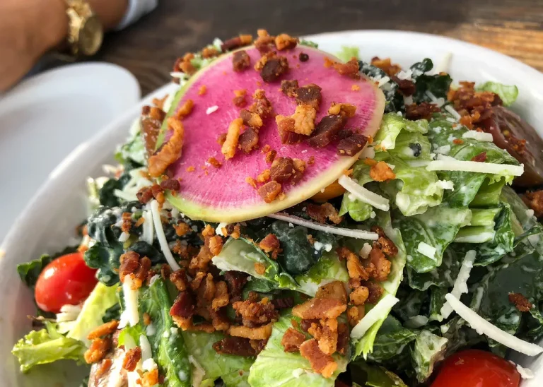 BLT salad with crispy bacon, romaine lettuce, cherry tomatoes, avocado, croutons, and creamy dressing in a large white bowl