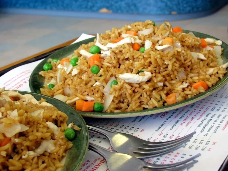Chinese fried rice with vegetables, scrambled eggs, and green onions served in a wok with chopsticks on the side