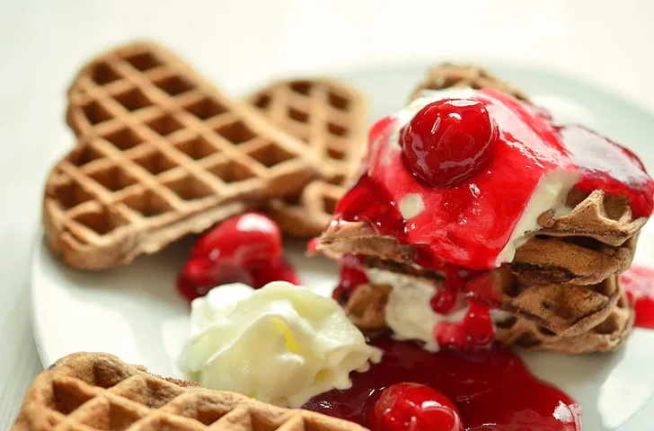 Golden Eggo French toast topped with maple syrup, fresh berries, and powdered sugar on a white plate