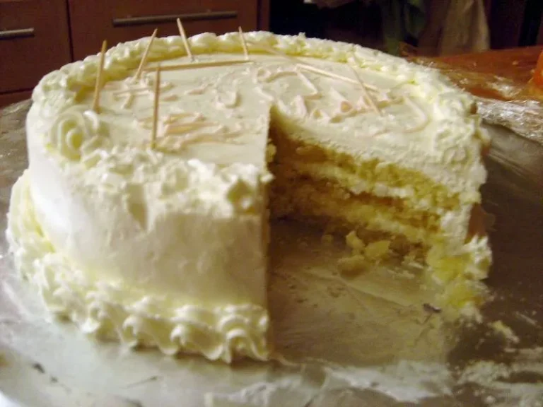 Classic Italian Cream Cake with cream cheese frosting, topped with toasted pecans and coconut flakes on a cake stand