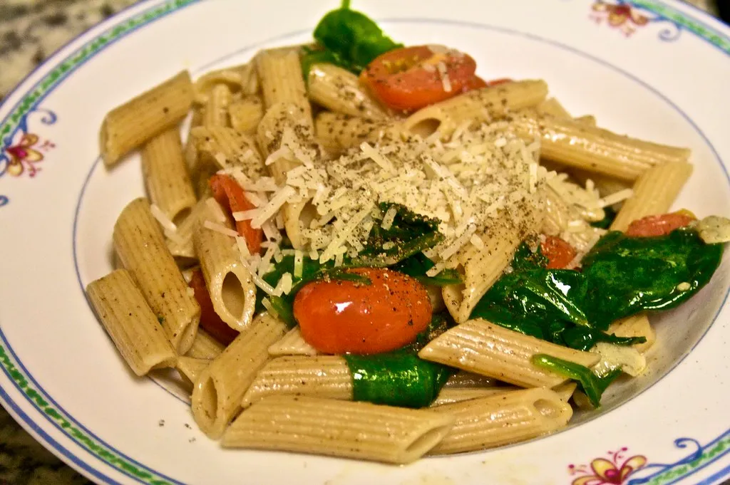 Colorful spinach pasta salad with cherry tomatoes, red onion, feta cheese, and spiral pasta tossed in a light olive oil dressing.