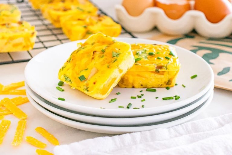 Golden slice of homemade Starbucks potato chive bake topped with melted cheese and fresh chives, served on a white plate.