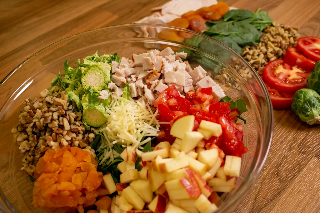 Chopped cooked turkey, celery, and onions laid out on a wooden cutting board”
