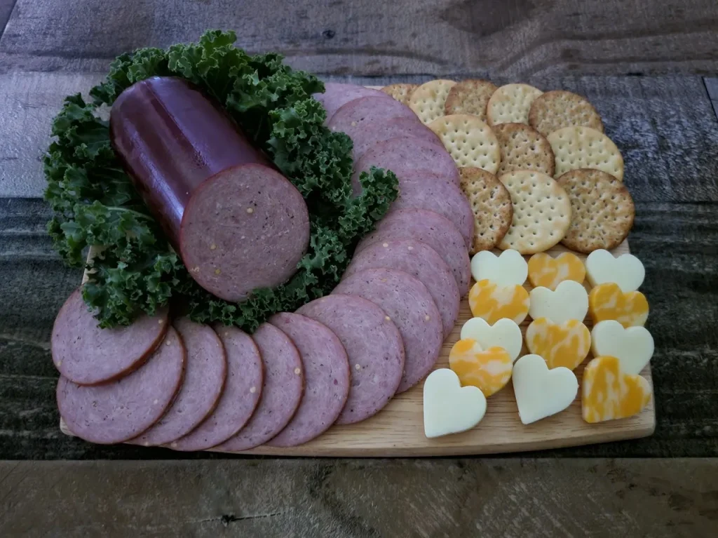 Homemade turkey summer sausage sliced on a wooden board with cheese and crackers