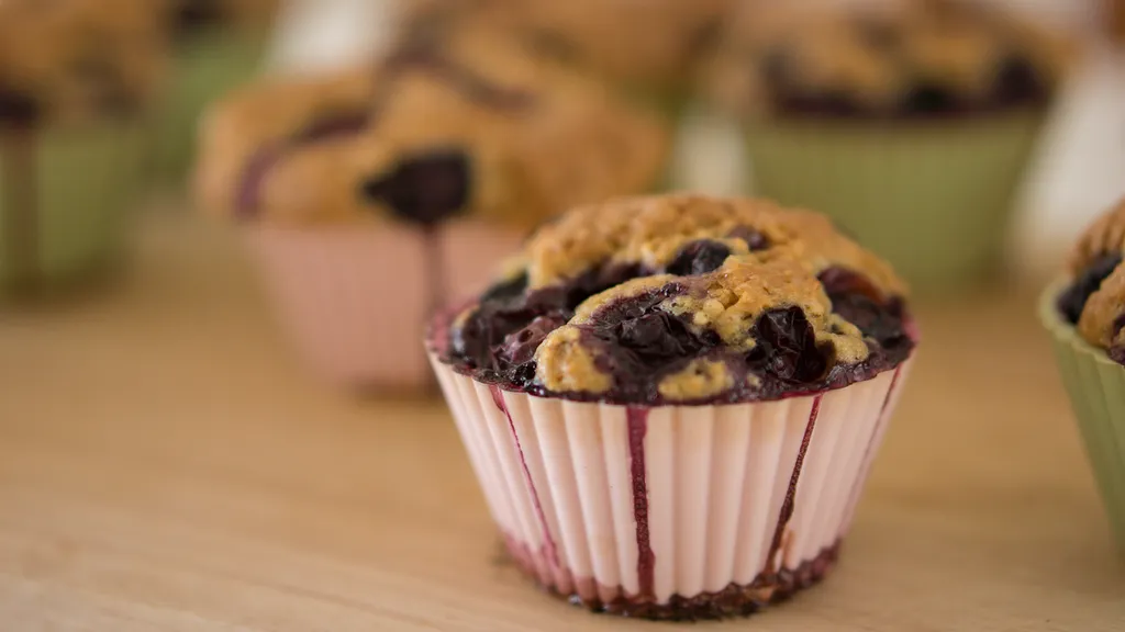 Freshly baked blueberry muffins with golden domed tops on a cooling rack