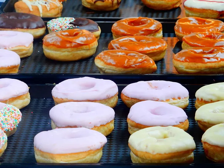 A colorful assortment of homemade donuts on a cooling rack with different glazes, sprinkles, and creamy fillings.