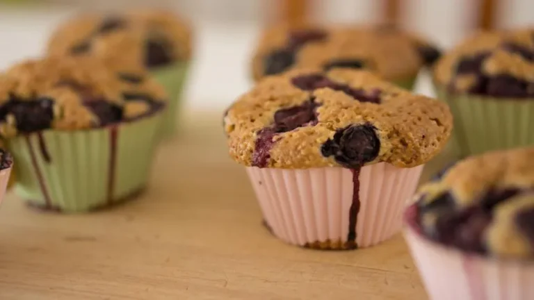 Freshly baked blueberry muffins with golden tops and juicy berries on a cooling rack