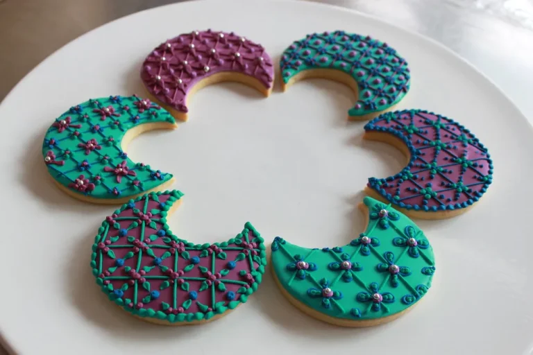 Crescent-shaped moon cookies decorated with pastel icing and edible glitter on a white plate