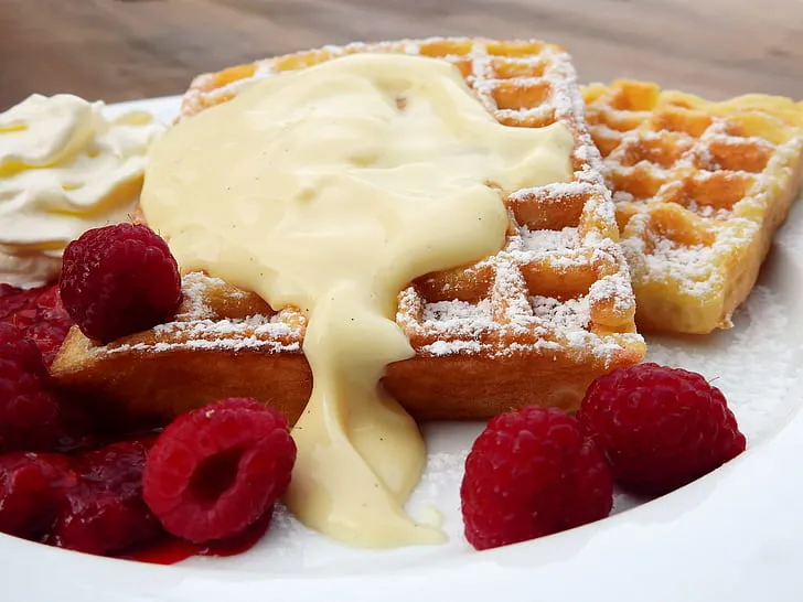 Golden Eggo French toast stacked on a plate with maple syrup, fresh berries, and a dusting of powdered sugar