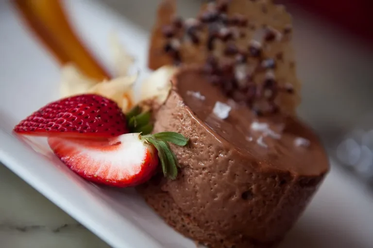 A glass dessert cup filled with rich chocolate mousse, topped with whipped cream and dark chocolate shavings.