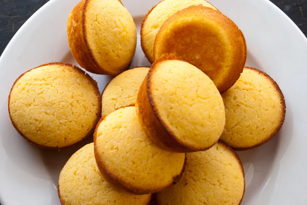 Golden honey cornbread muffins cooling on a wire rack with a drizzle of honey on top