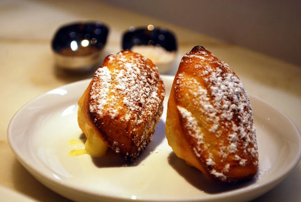 Golden lemon madeleines with powdered sugar on a plate with tea