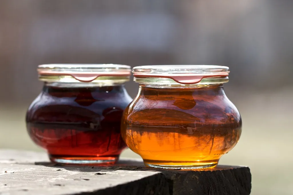Glass jar of homemade brown sugar pancake syrup with spoon on wooden table