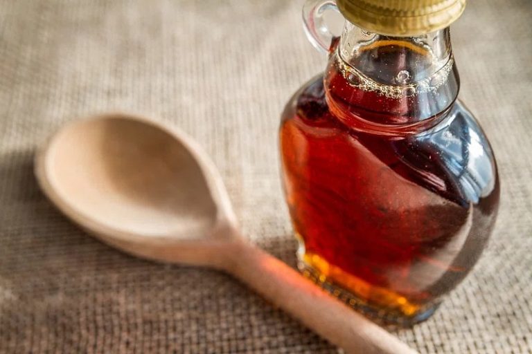 Homemade pancake syrup in glass jar with stack of pancakes and fresh berries on rustic table