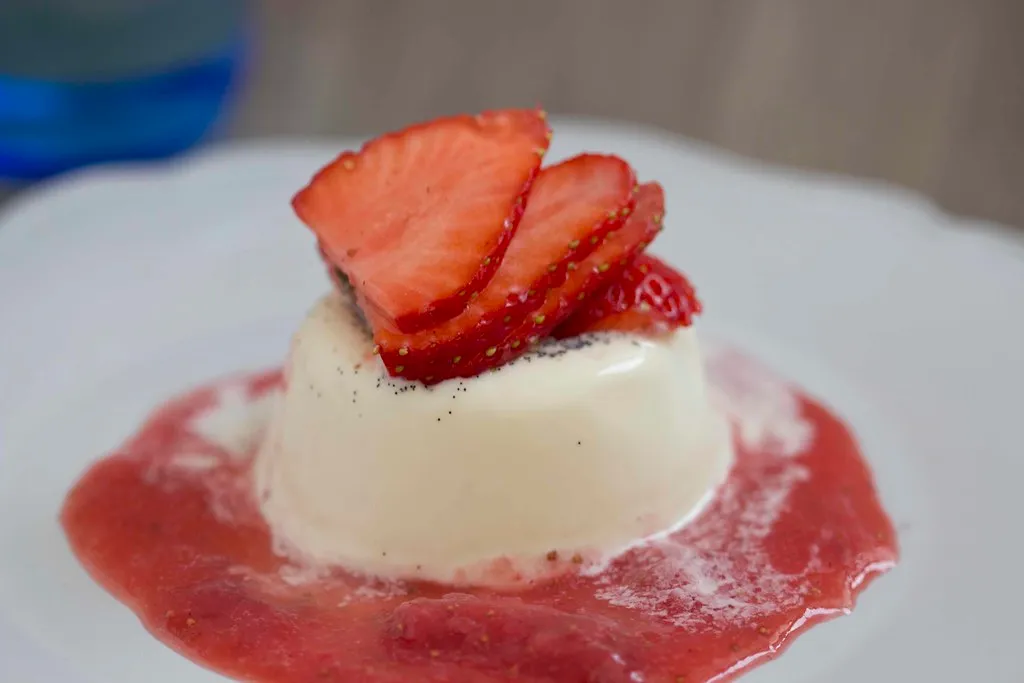 Creamy classic Italian panna cotta in a glass, topped with fresh berries and a mint leaf