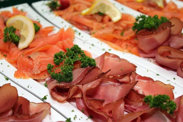 Smoked salmon breakfast bagel with cream cheese, capers, red onions, and fresh dill on a white plate.