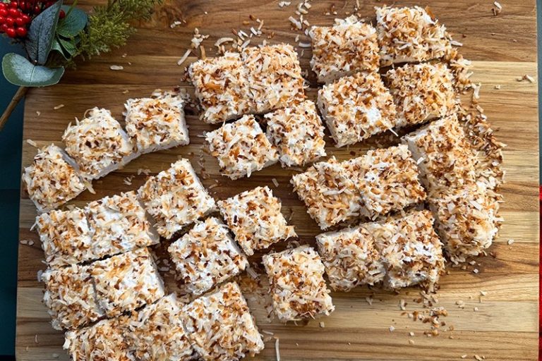 Soft and fluffy toasted coconut marshmallows coated with golden toasted coconut flakes on a rustic wooden board