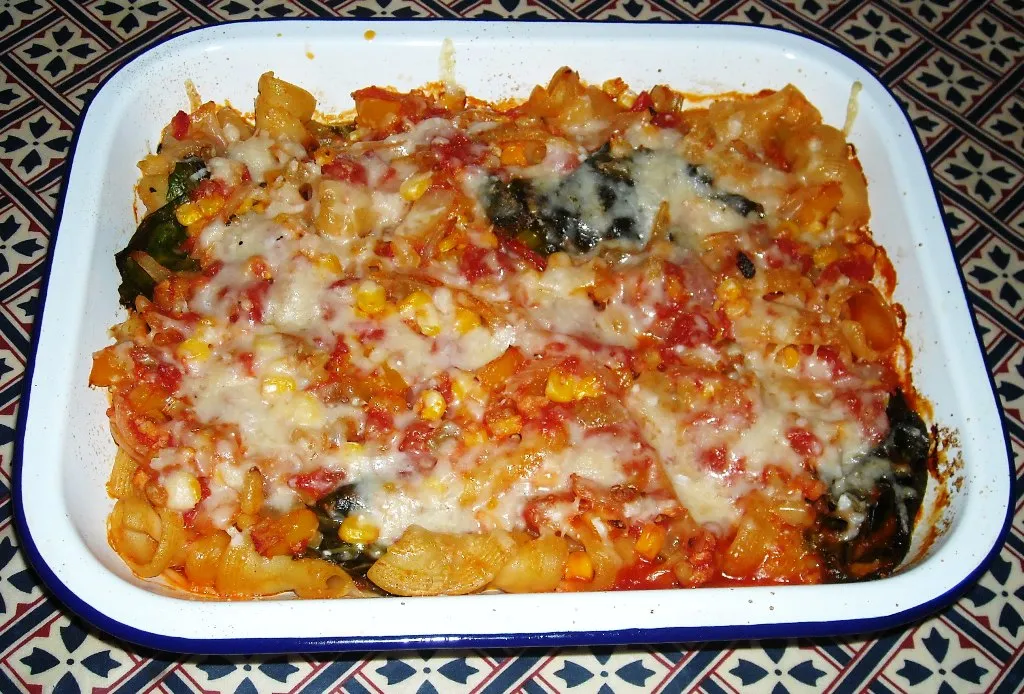 Baked vegan pasta casserole with vegetables and melted vegan cheese in a casserole dish