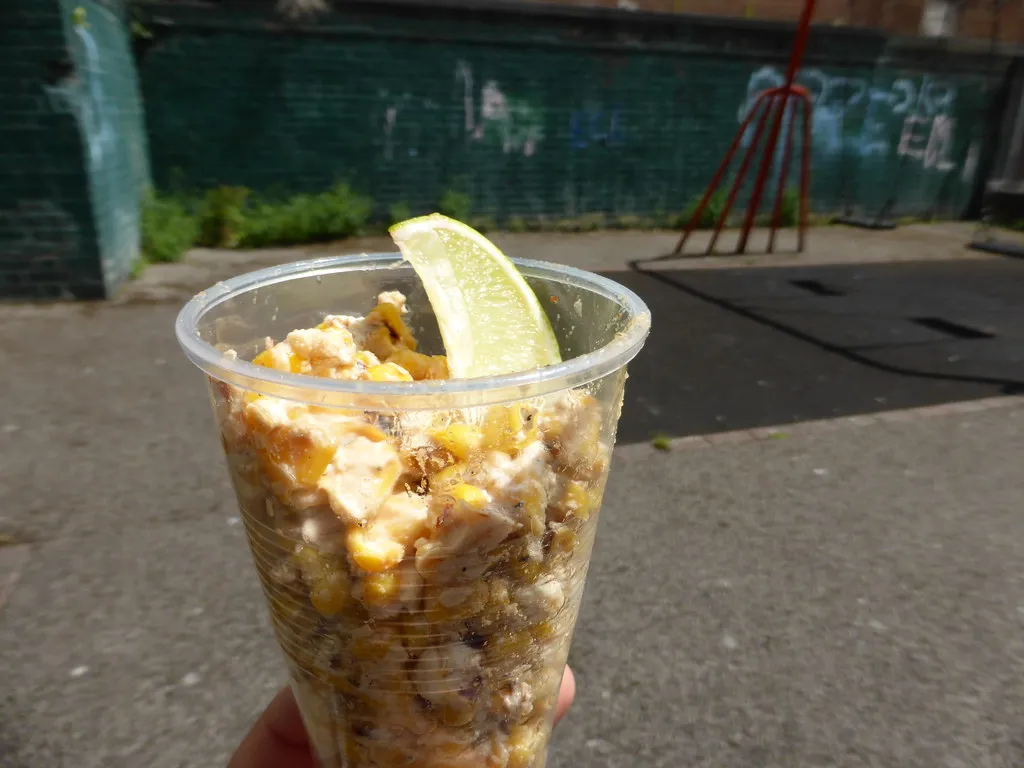 Bowl of creamy Mexican street corn salad (esquites) topped with cotija cheese, cilantro, and chili powder.