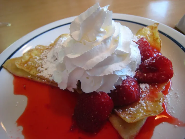 Delicious homemade strawberry crepes with fresh strawberries, whipped cream, and powdered sugar for breakfast