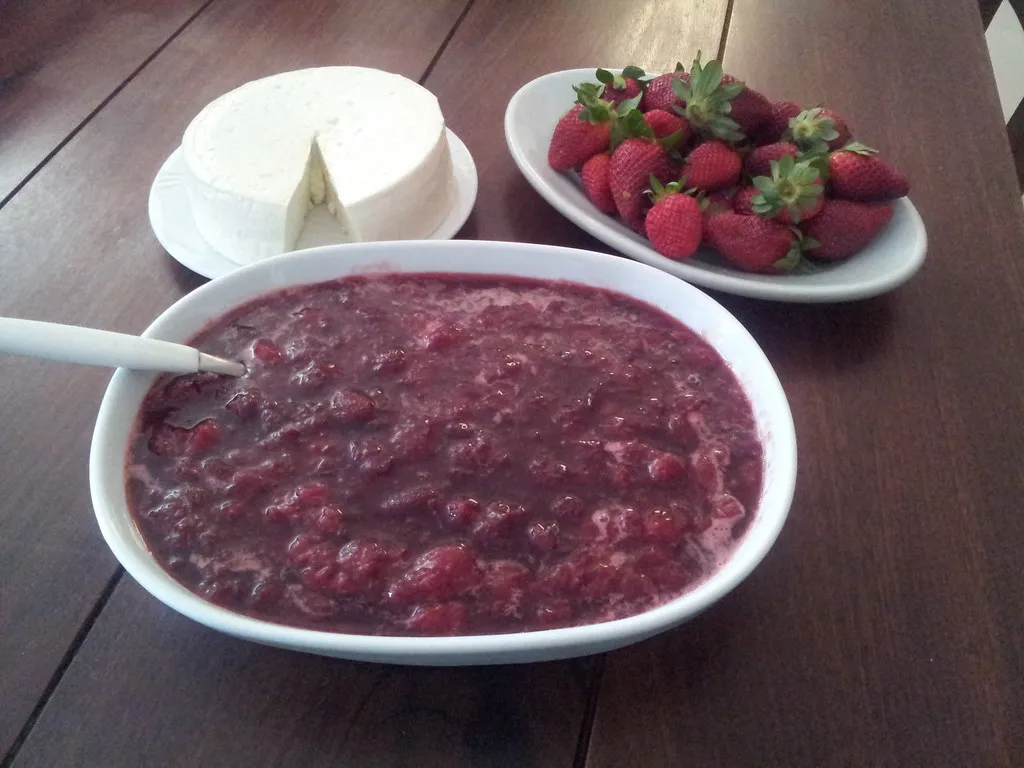 Homemade strawberry compote in a glass jar with fresh strawberries on the side