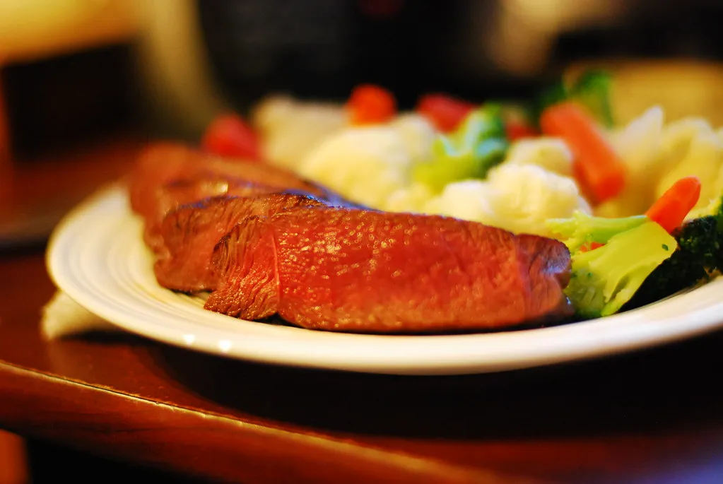 Pan-fried venison cube steak served with caramelized onions and mashed potatoes on a rustic plate