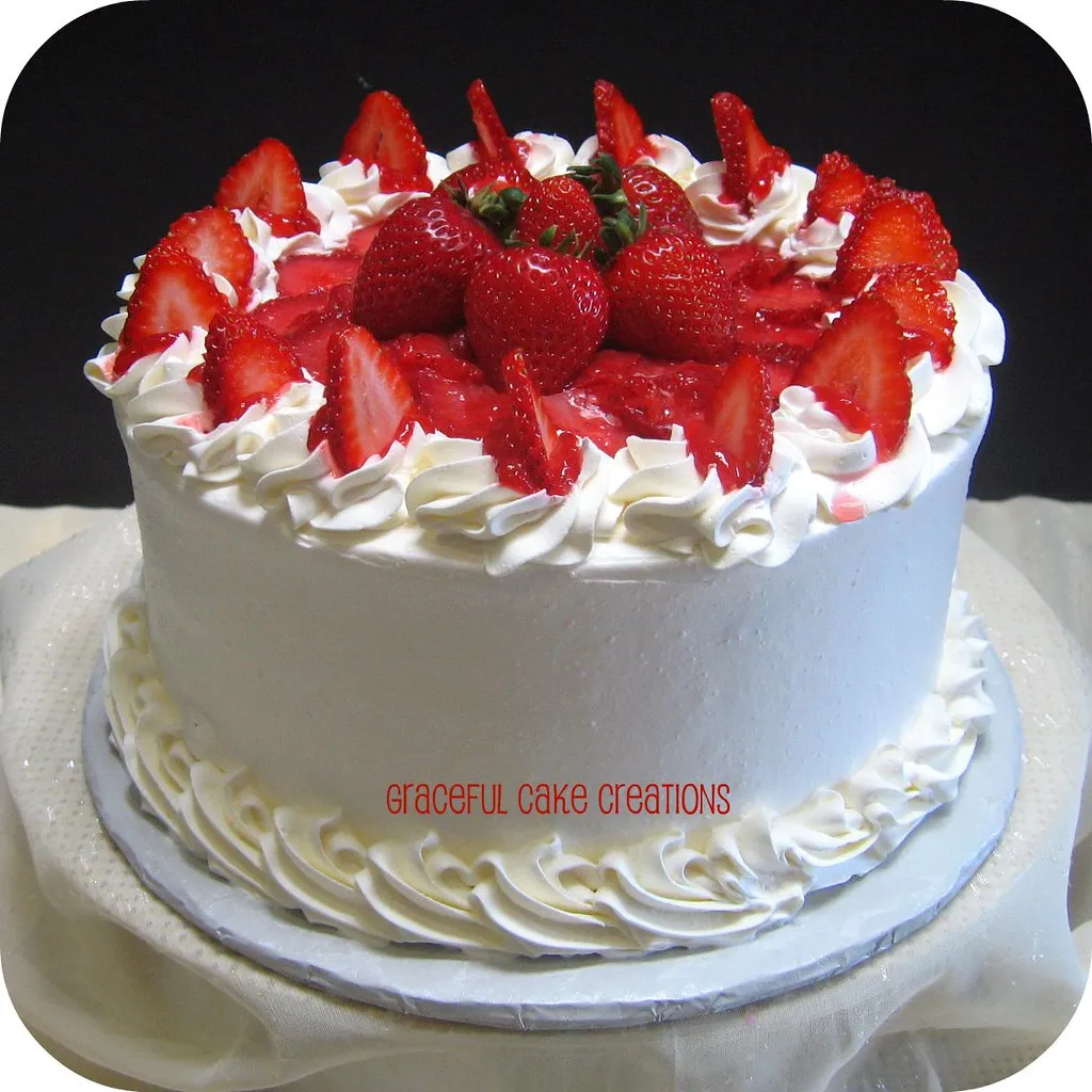 Homemade Gentilly cake with layers of whipped cream frosting and fresh strawberries, blueberries, and raspberries.