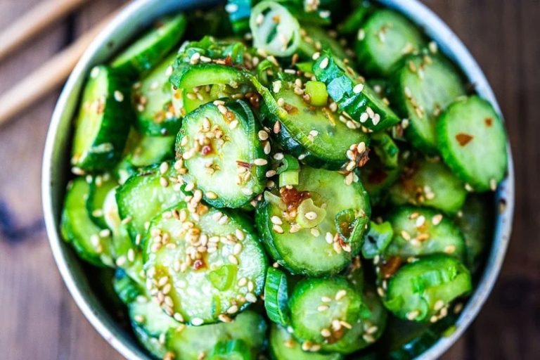 Close-up of colorful Thai cucumber salad with mint, lime, and chili on a rustic wooden table