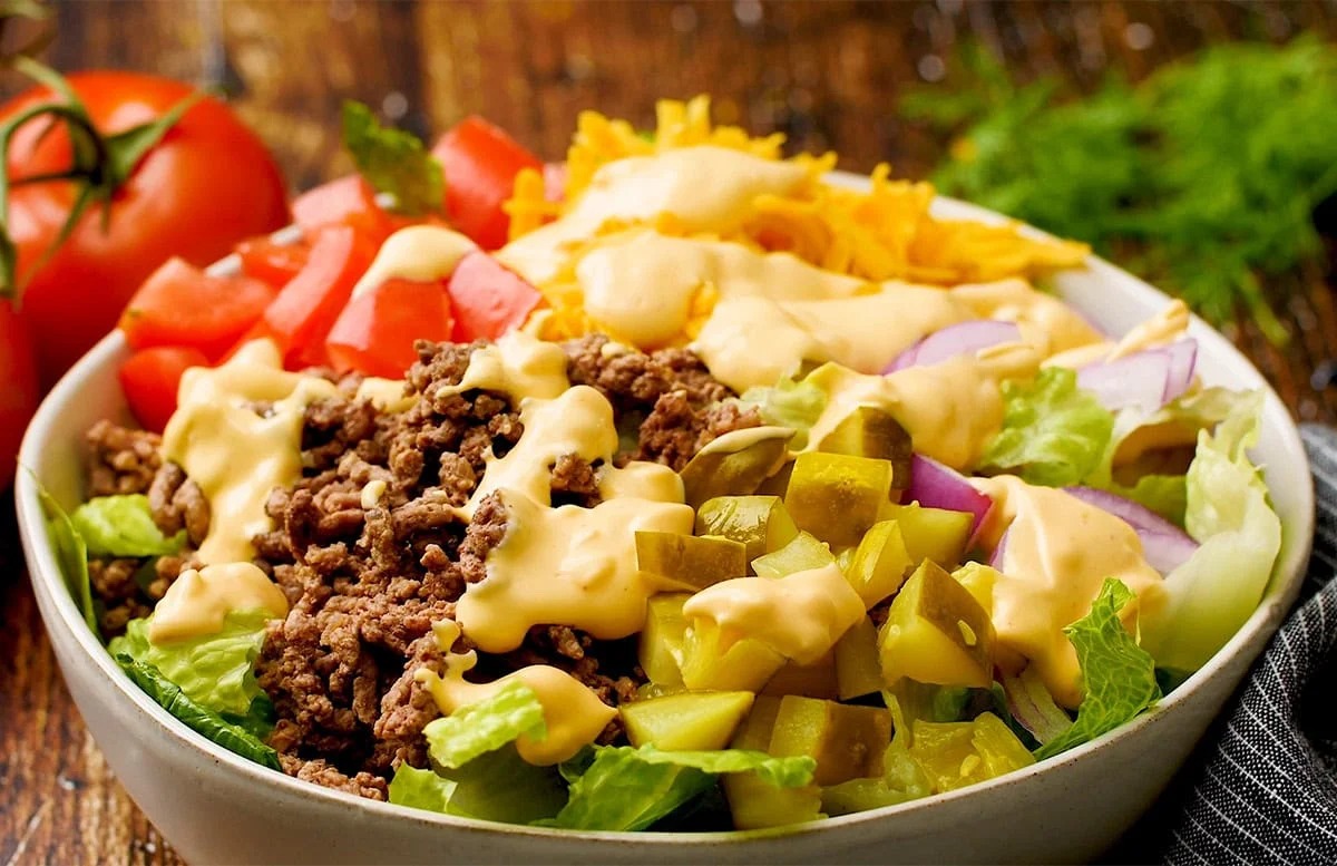 Fresh Big Mac salad served in a bowl with ground beef, shredded cheese, pickles, lettuce, and homemade copycat sauce