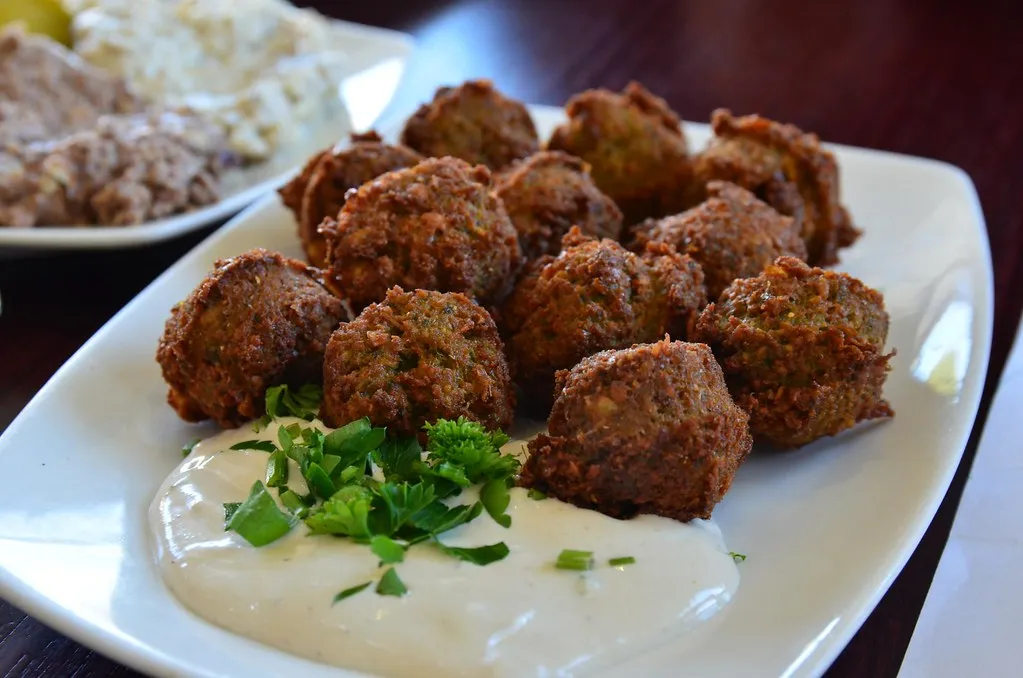 Falafel patties on a plate with tahini sauce and fresh parsley