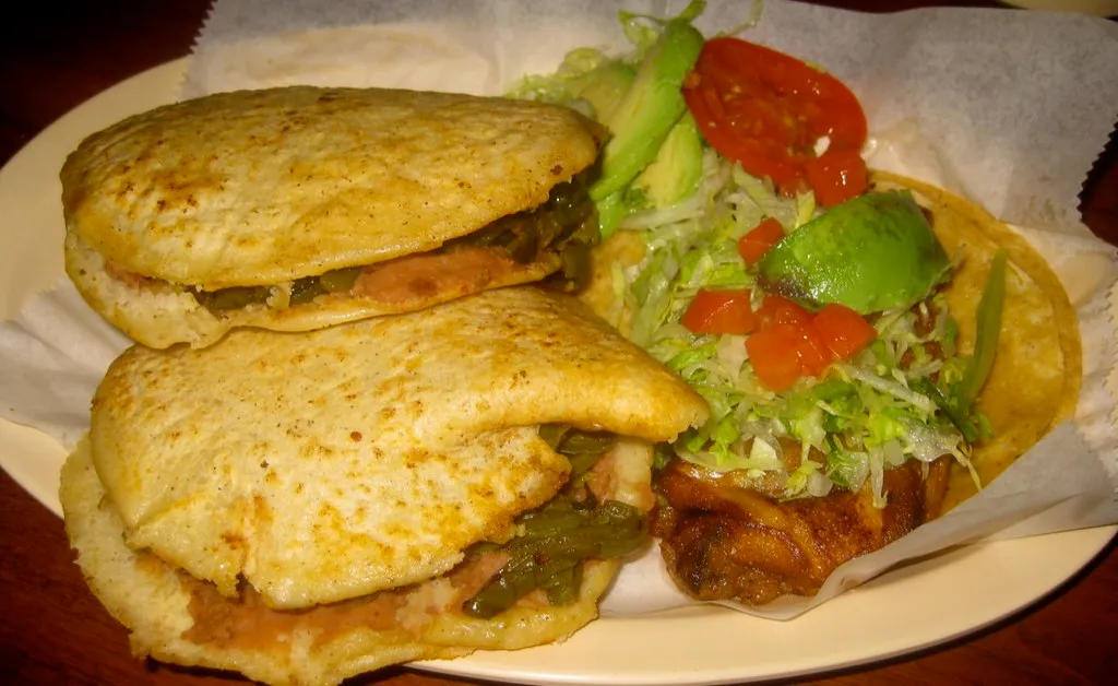 Homemade Mexican breakfast gorditas filled with eggs, beans, cheese, and salsa on a rustic plate