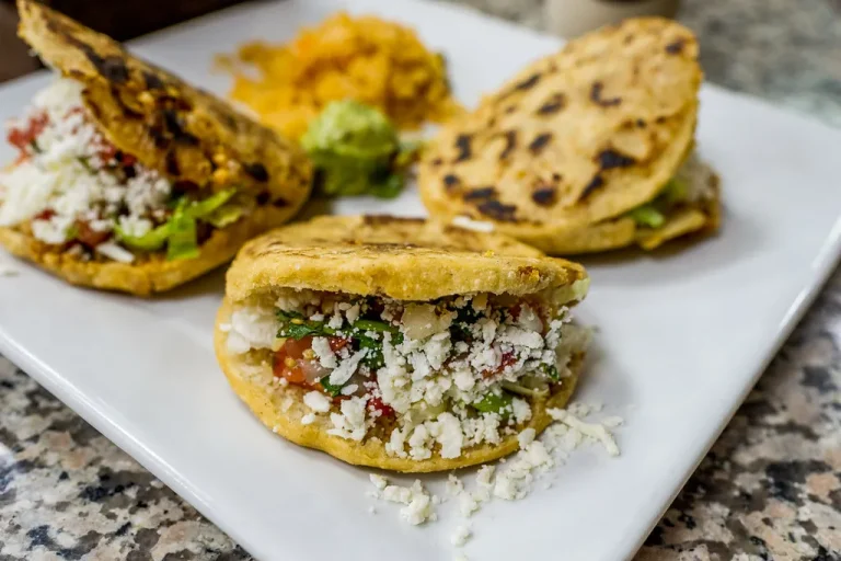 Authentic Mexican breakfast gorditas stuffed with eggs, beans, cheese, and salsa served with avocado on a rustic plate