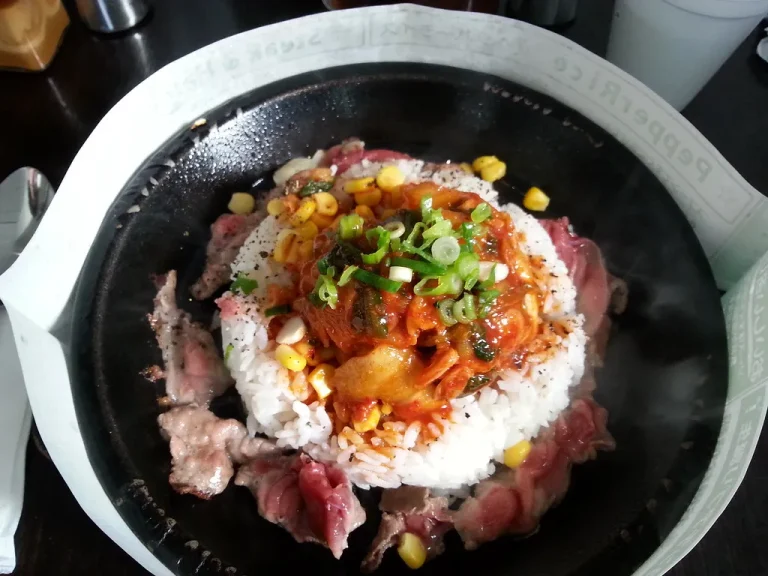 Sizzling Pepper Lunch-style beef pepper rice with garlic butter, corn, and green onions served on a hot cast iron skillet.