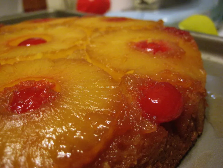 Moist and fluffy pineapple juice cake topped with fresh pineapple slices and shredded coconut on a white plate, ready to serve.