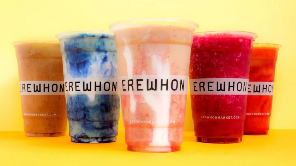 Close-up of a pink Hailey Bieber smoothie in a tall glass with fresh strawberries on top and a creamy strawberry glaze swirl.