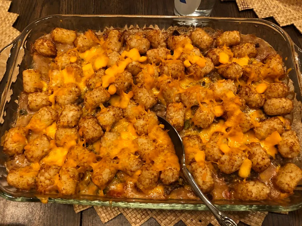 Golden cheesy tater tot breakfast casserole with sausage, eggs, and melted cheddar in a baking dish.