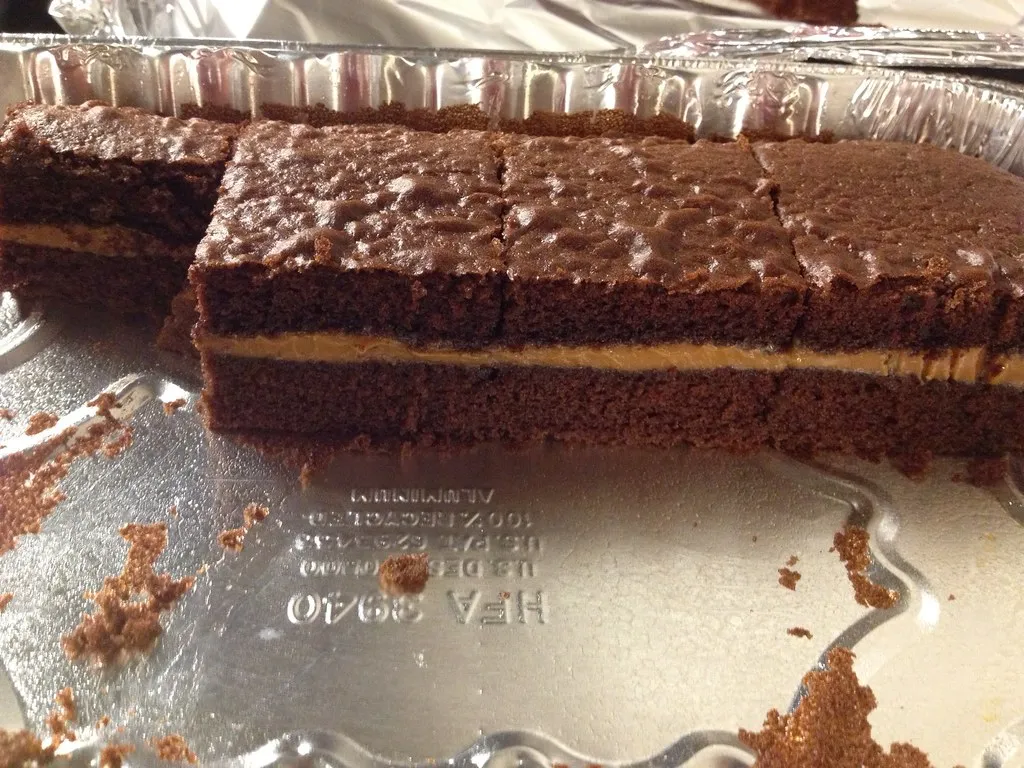 Homemade turtle cake topped with caramel drizzle, pecans, and chocolate ganache
