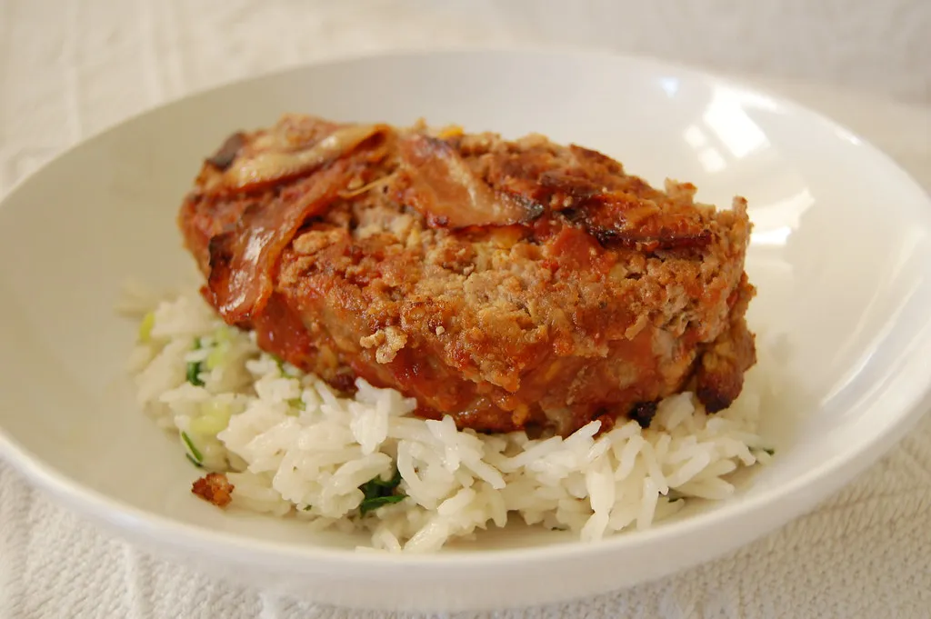 Sliced chicken meatloaf with a tangy glaze, served with creamy mashed potatoes and steamed vegetables for a healthy comfort meal.