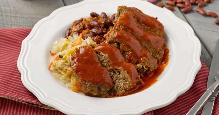Sliced juicy meatloaf with rich onion flavor from Lipton onion soup mix on a white plate with vegetables.