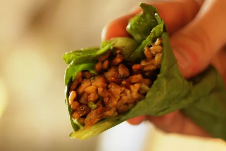 Spicy gochujang lettuce wraps with chicken, sesame seeds, and scallions served on a white plate