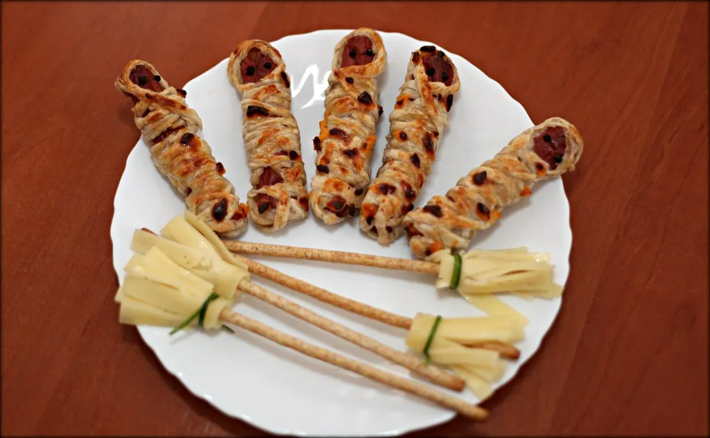 Halloween-themed savory appetizers arranged on a festive table with spooky decorations and candles.